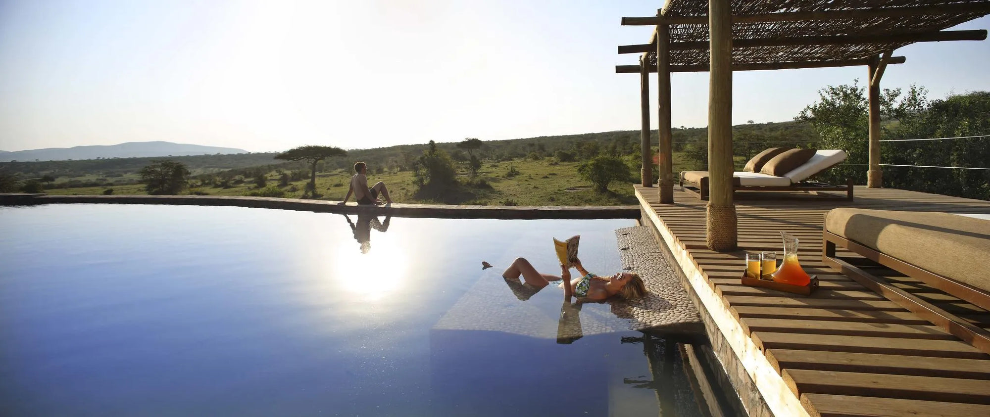 relaxing by the heated infinity pool at the spa village at Mara Bushtops Camp, Masai Mara, Kenya.