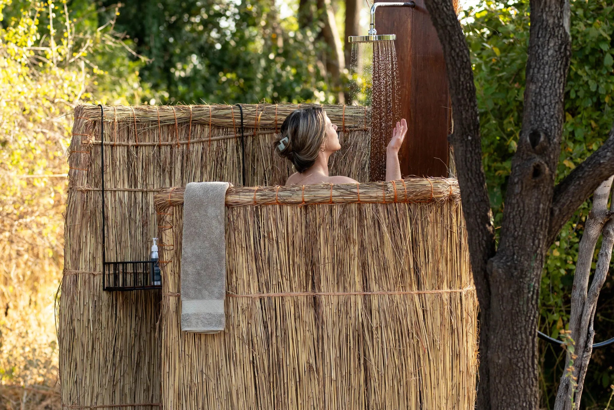 Kokoko - Guest Having an Outdoor Bucket Shower at Kokoko Camp, Ruaha National Park, Tanzania.